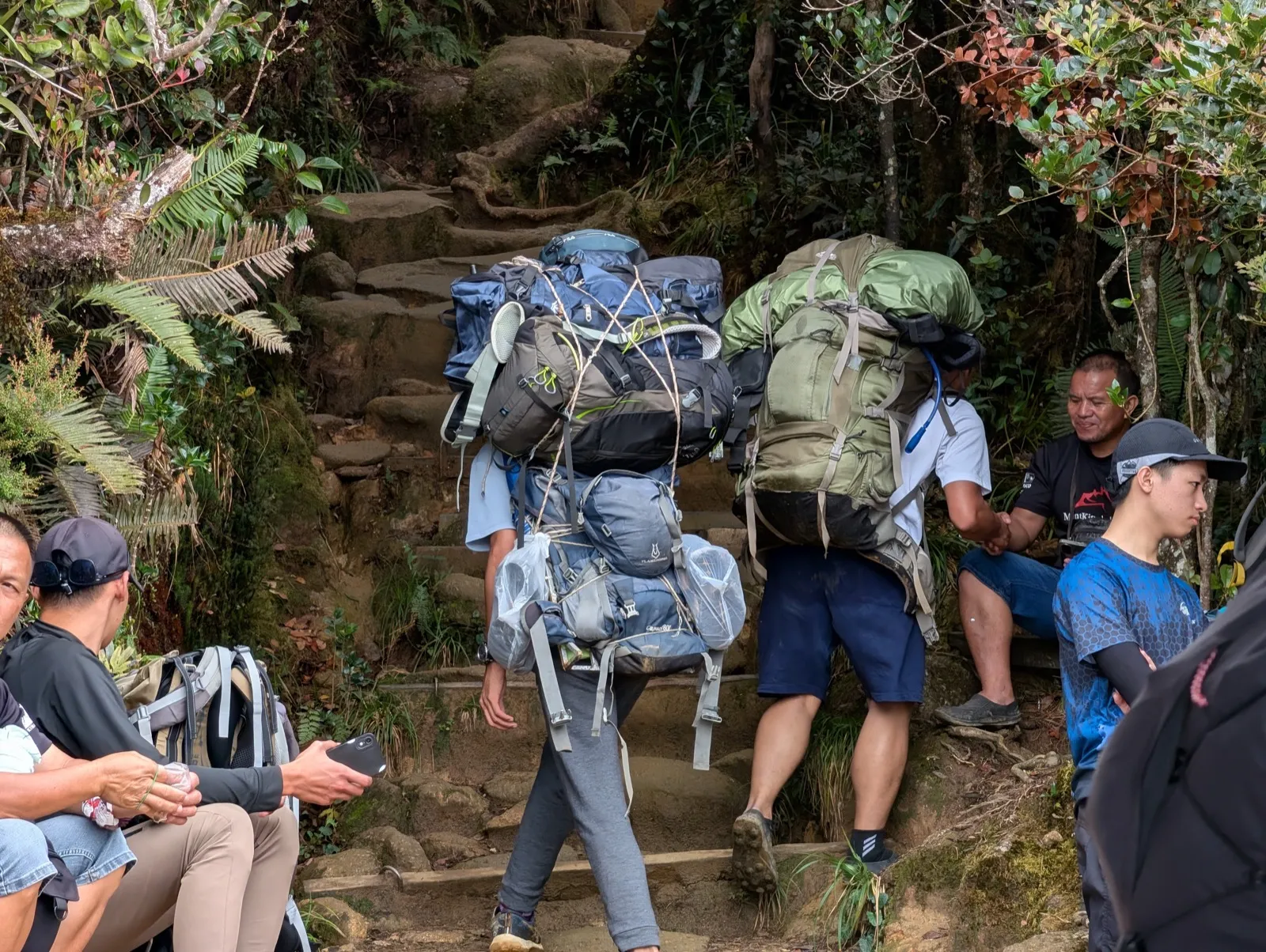 Porter carrying multiple packs uphill